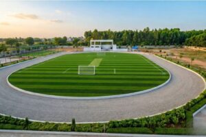 Aerial view of the world-class green sports turf and athletic track at Aadya Academy, one of the best schools in Bangalore with sports facilities.