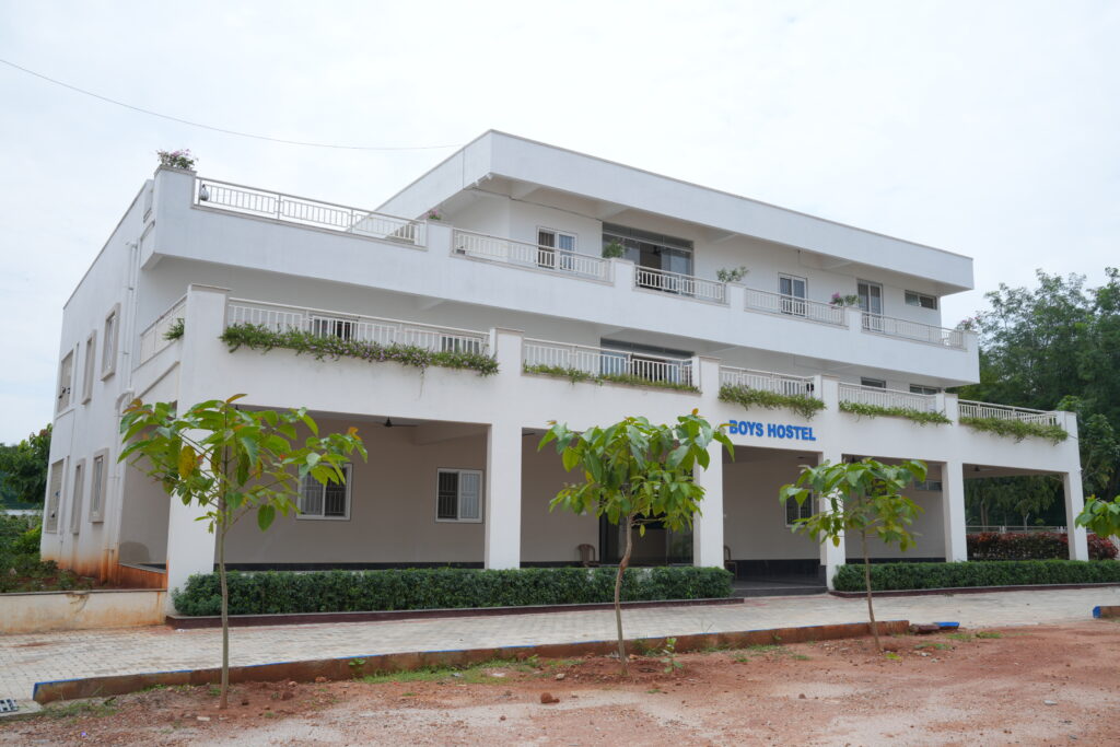 Exterior view of the multi-story Boys Hostel block with balconies and landscaped entrance at Aadya Academy Budigere campus