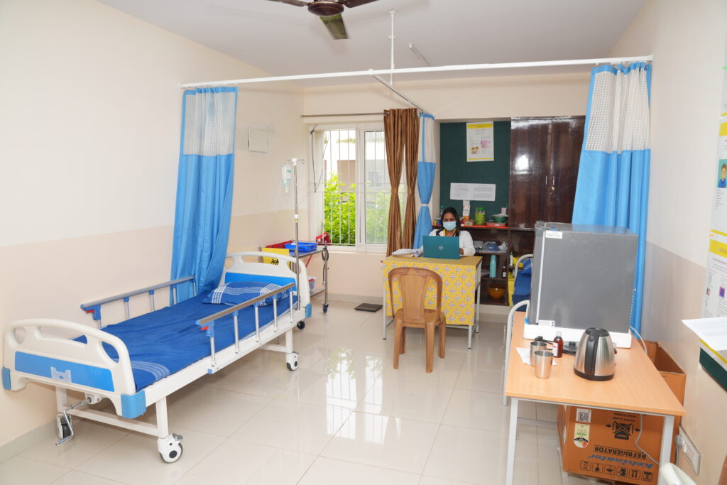 Clean campus infirmary room at Aadya Academy Budigere featuring a patient bed, medical attendant, and health care facilities